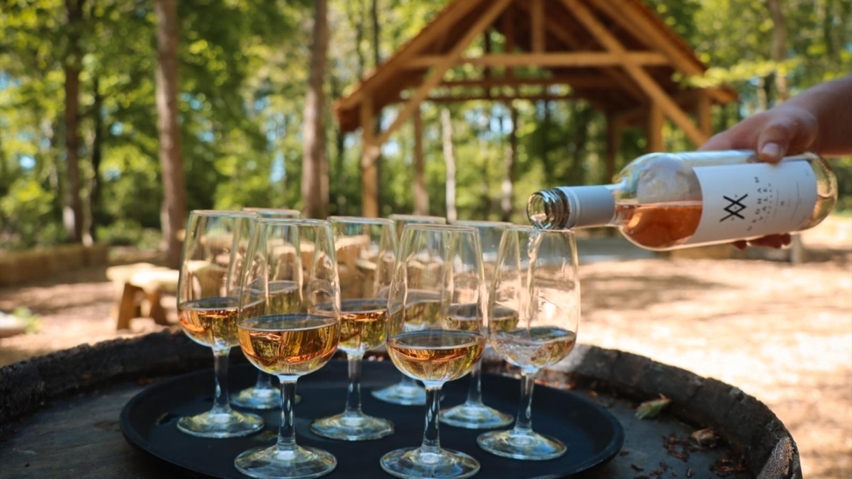 Pouring wine into glasses on a tray, Dedham Vale Vineyard, Essex